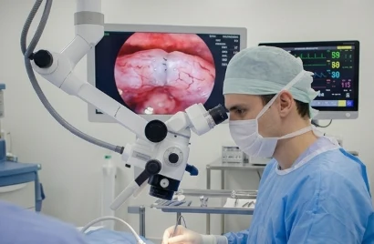 Cirurgião olhando pelo microscópio cirúrgico com imagem ampliada no monitor
