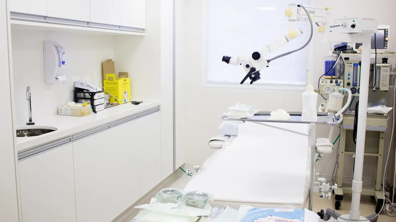 Sala de procedimentos com mesa cirúrgica e microscópio