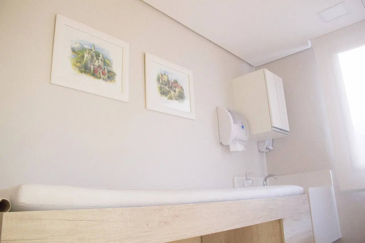 Sala de exame com maca e quadros decorativos
