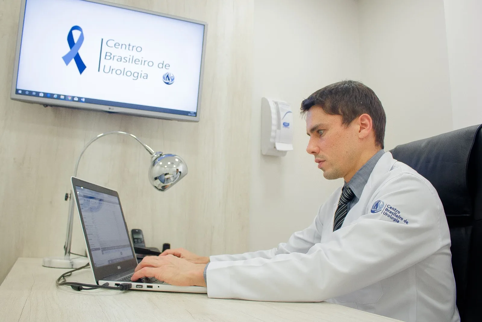 Dr. Diego Reis Delgado atendendo em consultório, registrando informações no computador